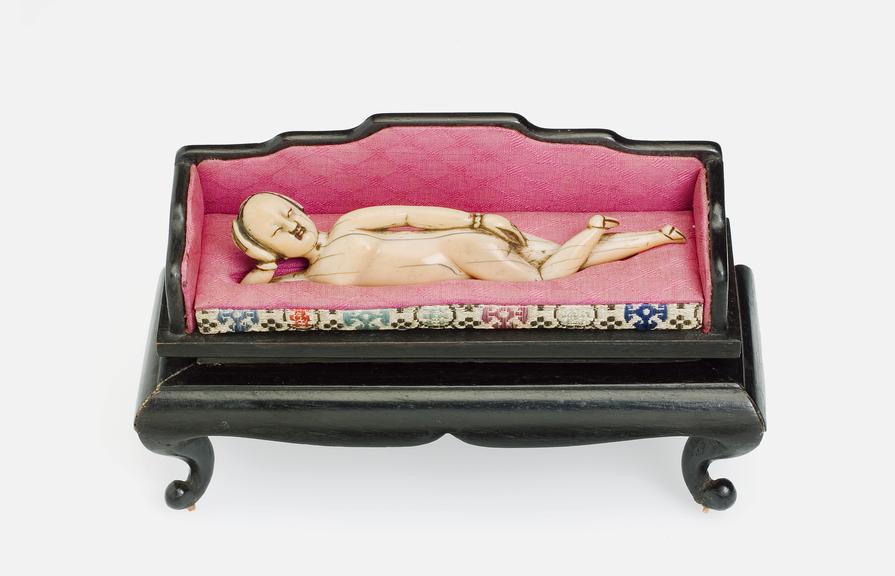 Ivory figure of a woman reclining on upholstered wooden couch (diagnostic figures)