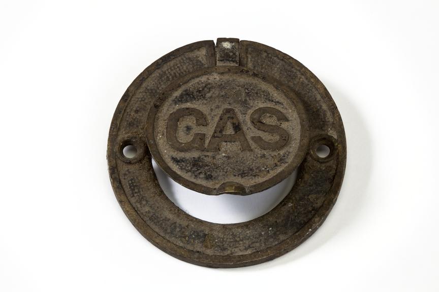 Gas cock cover plate photographed from above on a white