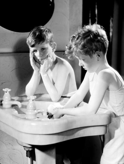Two boys washing at a sink