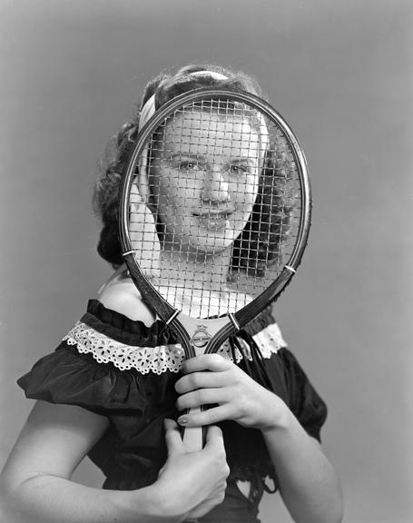 Woman looking through a tennis racket