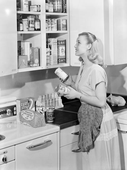 Woman putting tins in a cupboard