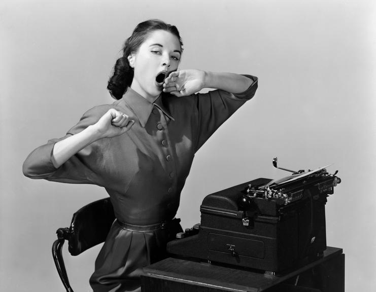 Woman yawning at a typewriter