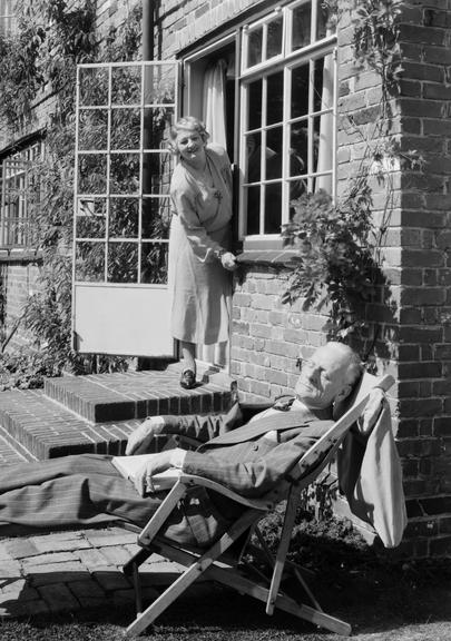 Woman calling to a man asleep in a deckchair