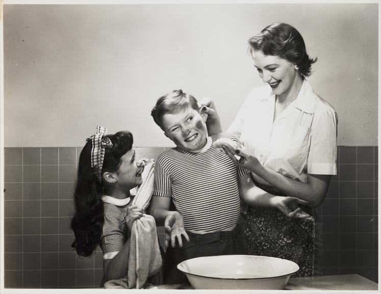 Mother and daughter washing son's face
