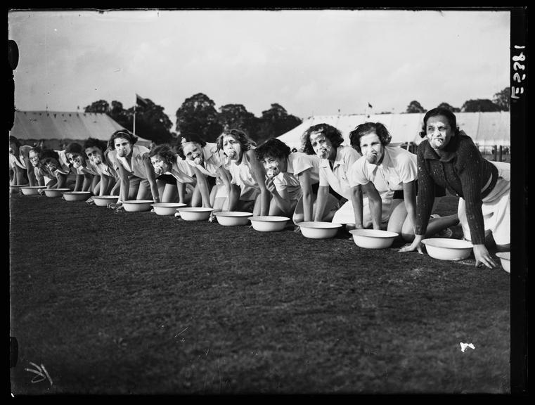 Women ducking for apples
    A photograph of a long line of women