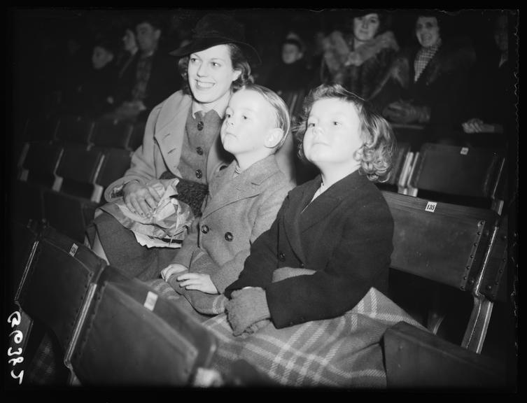 Mother and children watching circus rehearsal
    A photograph of