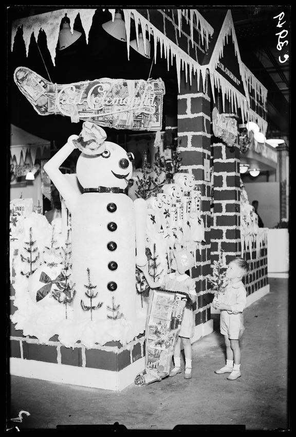 Two children looking at a sales display with a giant snowman
    A