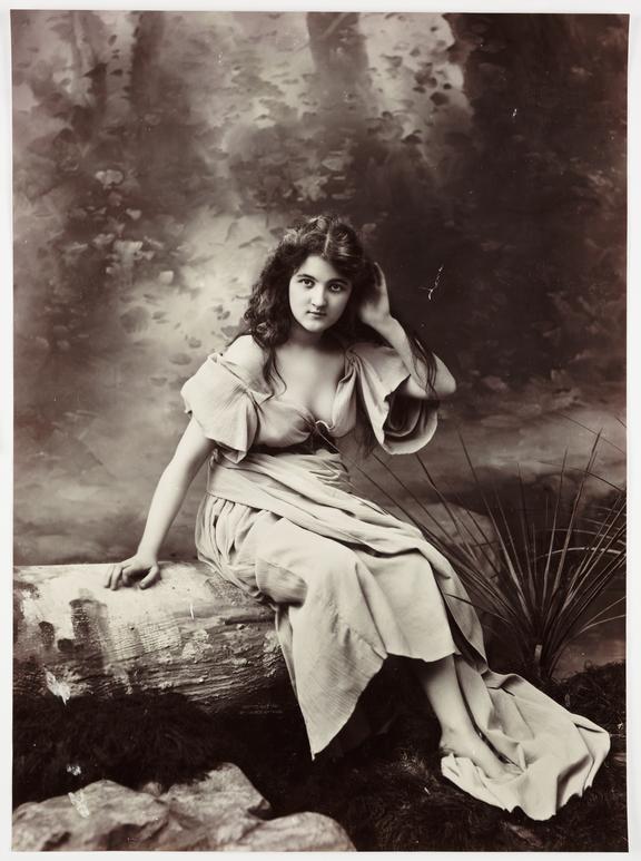 Young woman seated on a tree trunk
    A studio photograph of a