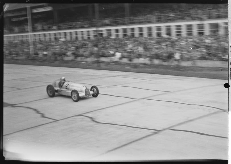 Luigi Fagioli driving Mercedes-Benz racing car past the pits