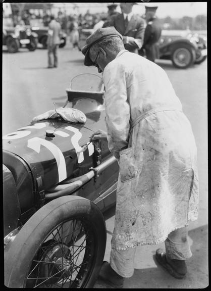 Sign-writer painting the number 12 on side of Austin racing car