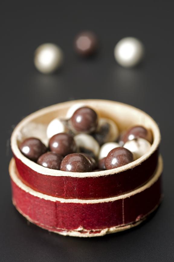 Small round cardboard Maroon coloured pill box containing