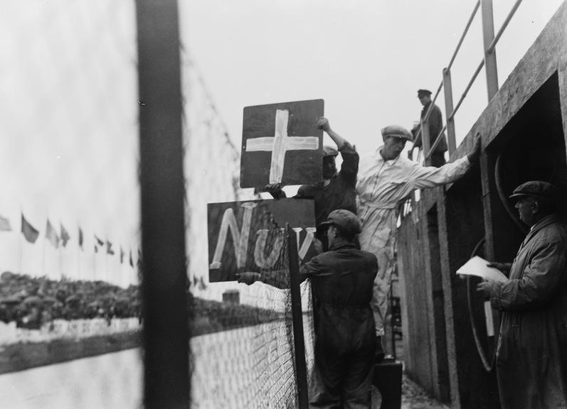 Mechanics holding up pit board signs