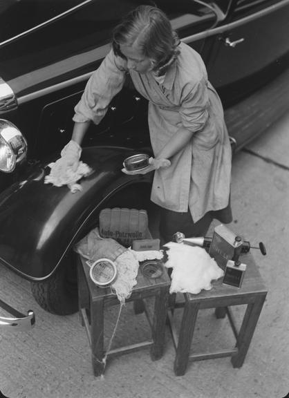 Woman polishing exterior of car with 'Simoniz'