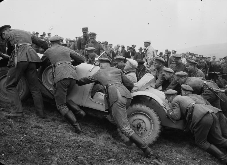 Soldiers pushing a car up a hill