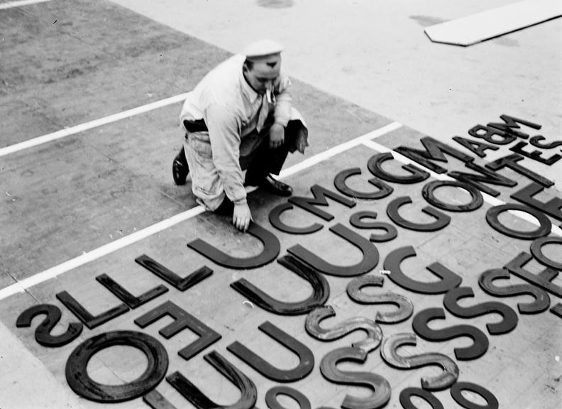 Man reaching down to pick up a letter for a sign