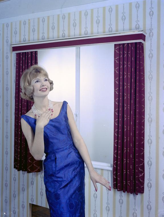 Glamorous woman touches pearl necklace beside window