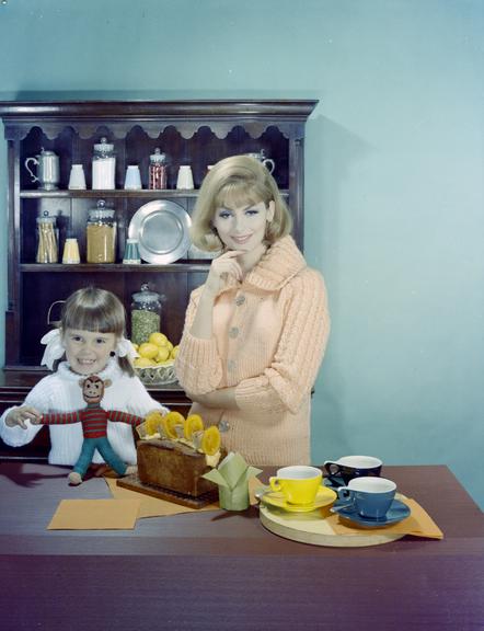 Woman & child wearing knitwear pose beside tea things