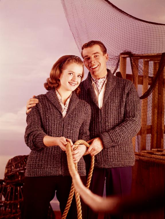 Couple wearing knitted cardigans holding rope