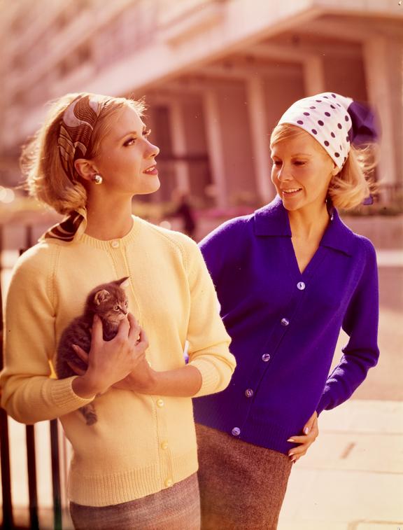 Woman looks at another holding kitten