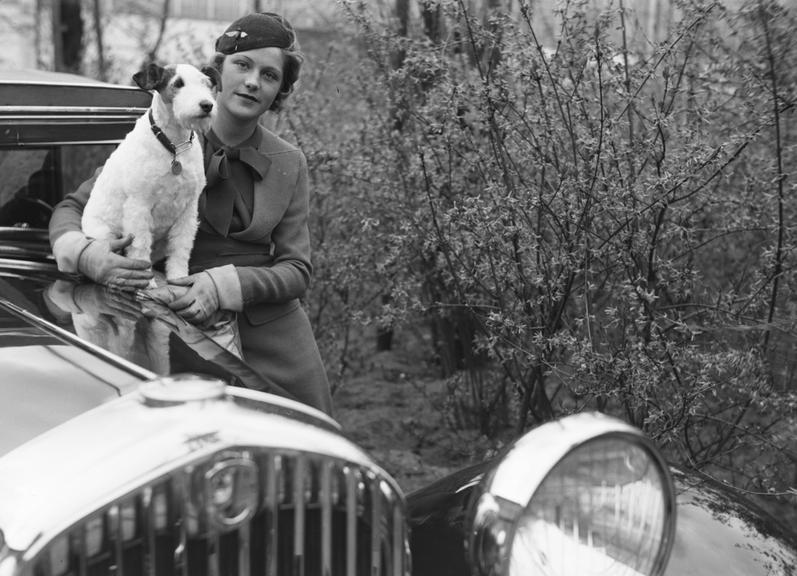 Woman with dog poses with car