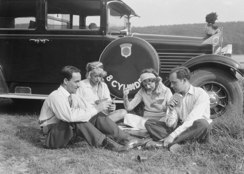 Group play cards beside Stoewer 8 cylinder car