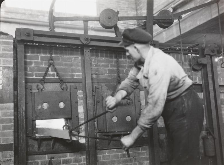 Man places metal in furnace at a cable works factory