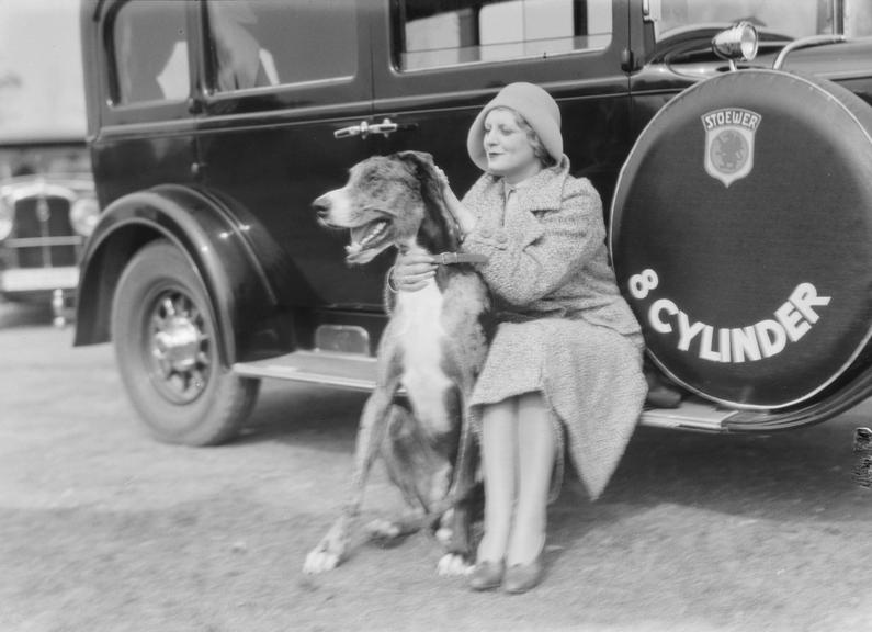 Woman with dog sits on 8 cylinder Stoewer car