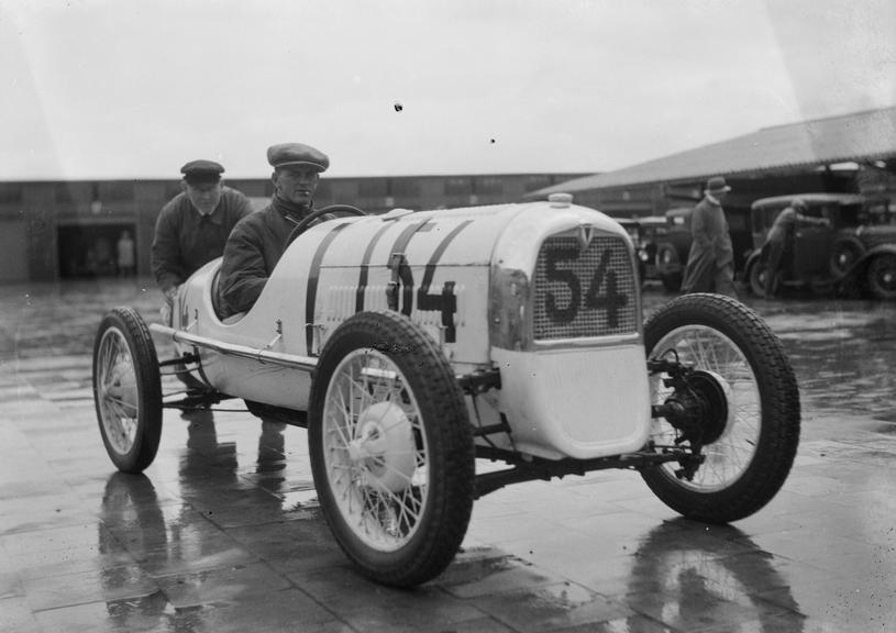 Man pushes a racing car with driver at the wheel