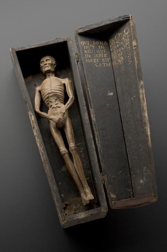 Wooden statue, carved of a dead man, in miniature coffin