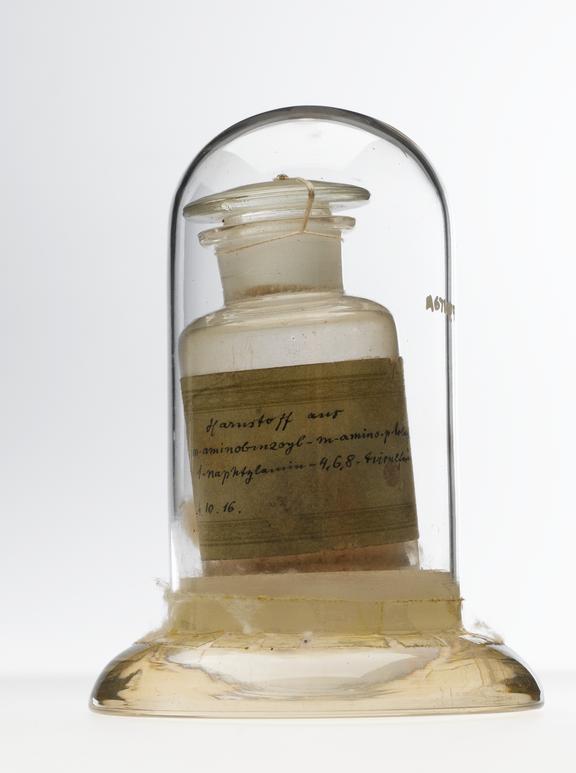 Clear glass bottle, stoppered, containing specimen of Bayer 205