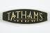 Two matching halves of Tatham's nameplate from textile