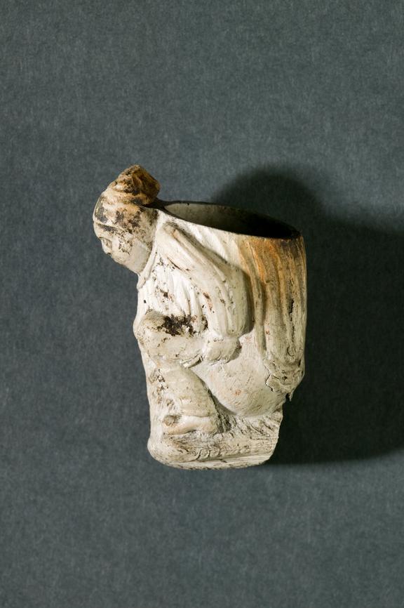 Clay tobacco pipe bowl depicting a man crouched over whilst