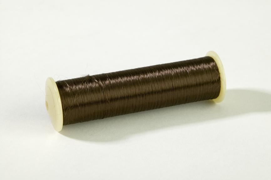 Bobbin for ribbon loom with brown thread
Photographed on a