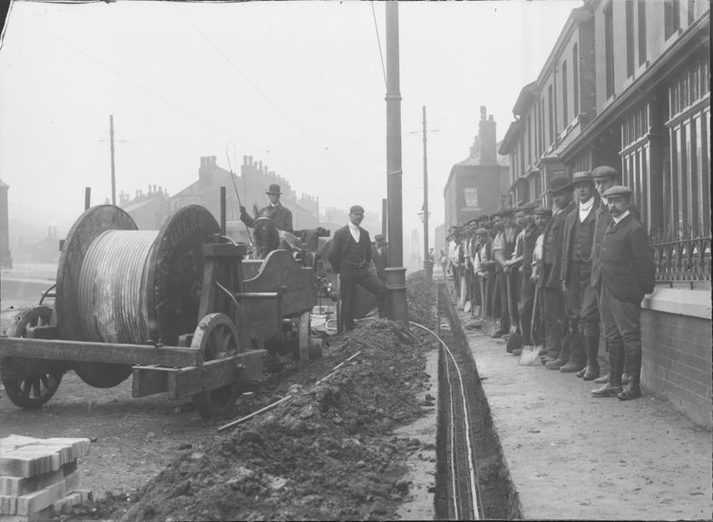 Works photographic negative of a team of men laying cable