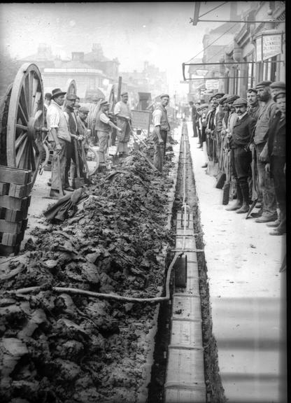 Works photographic negative of men laying cable