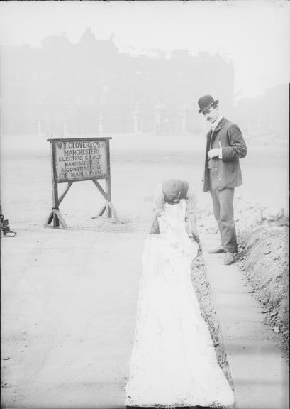 Works photographic negative of man beside filled-in trench