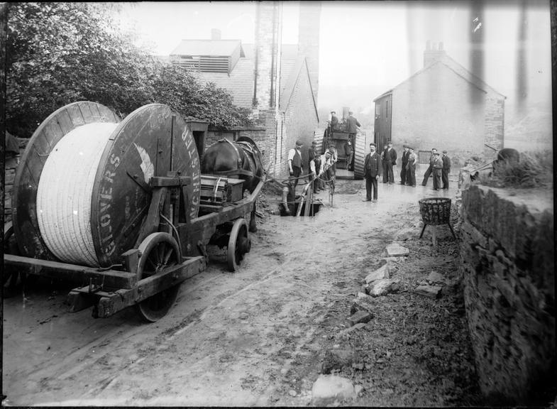 Works photographic negative of cable being pulled from manhole