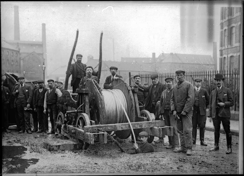 Works photographic negative of cable being fed into a manhole