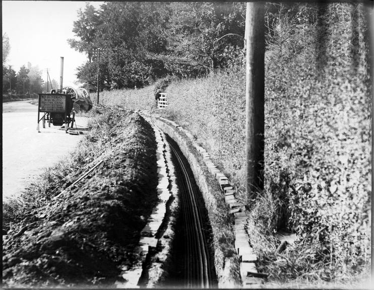 Works photographic negative of cables in trench by rural road