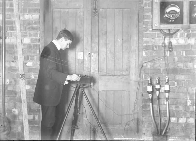 Works photographic negative of a man with instrument on tripod