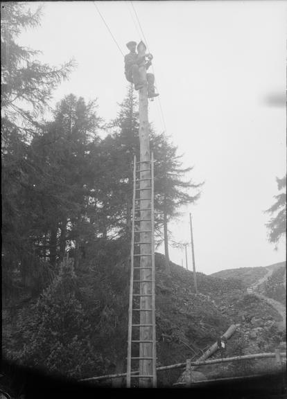 Works photographic negative of man installing wire on pole