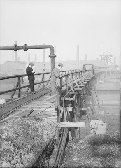 Works photographic negative of cable on pipe gantry