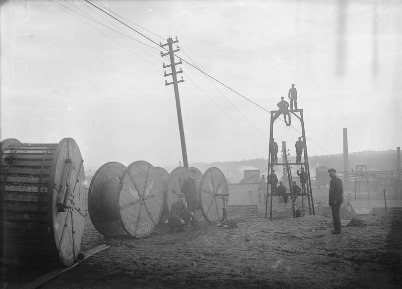 Works photographic negative of men attaching suspension cable