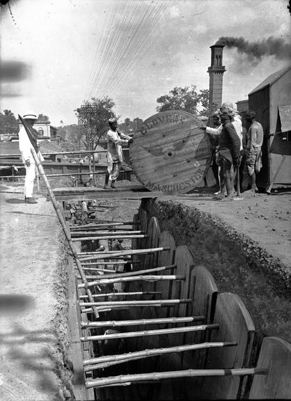 Works photographic negative of men rolling cable drum