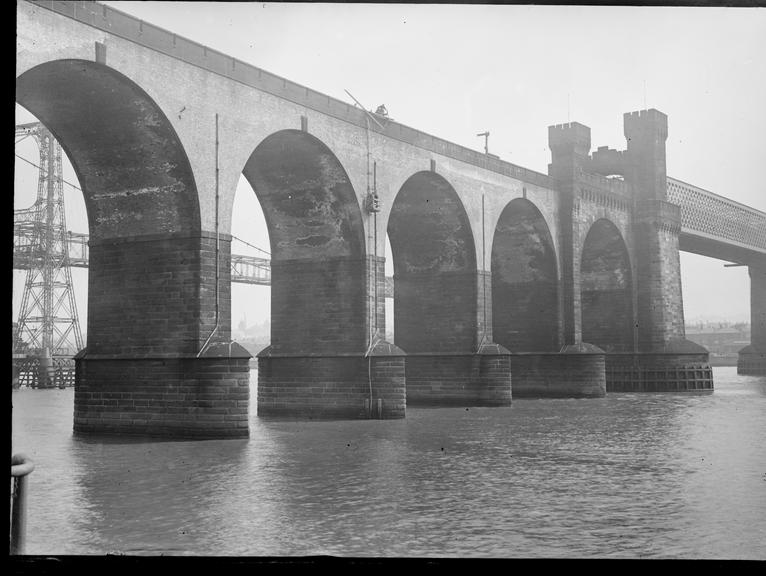 Works photographic negative of men attaching cables to masonry