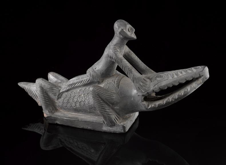 Black earthenware foot-scraper in the form of a man riding a