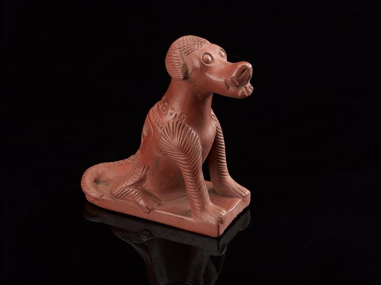 Red earthenware foot scraper in the form of a sitting dog