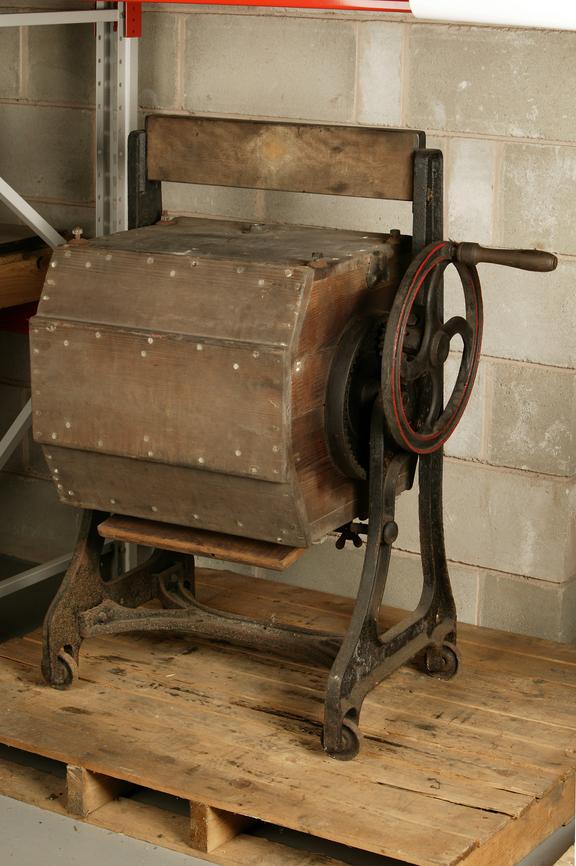 Hand turned washing machine; small flywheel turns main wooden