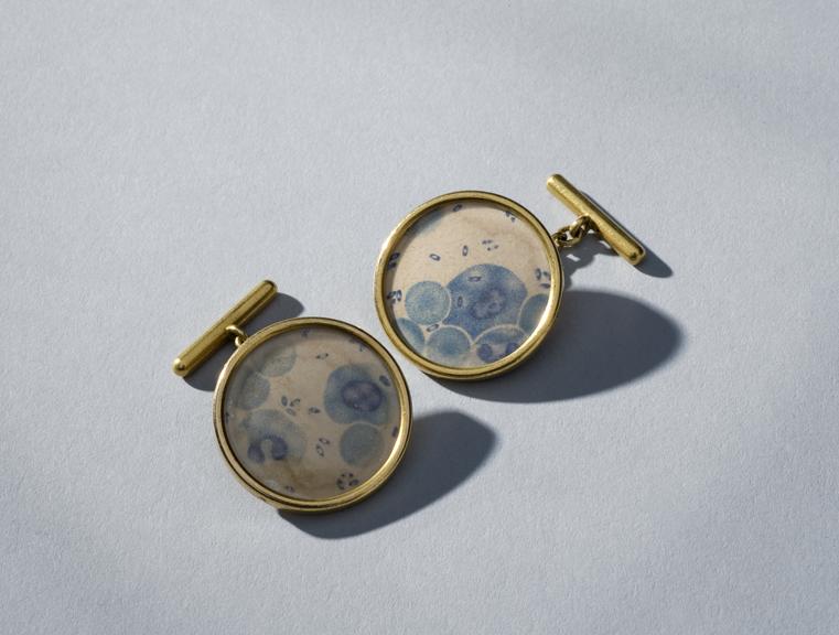 Two cuff links, gold, showing plague bacillus