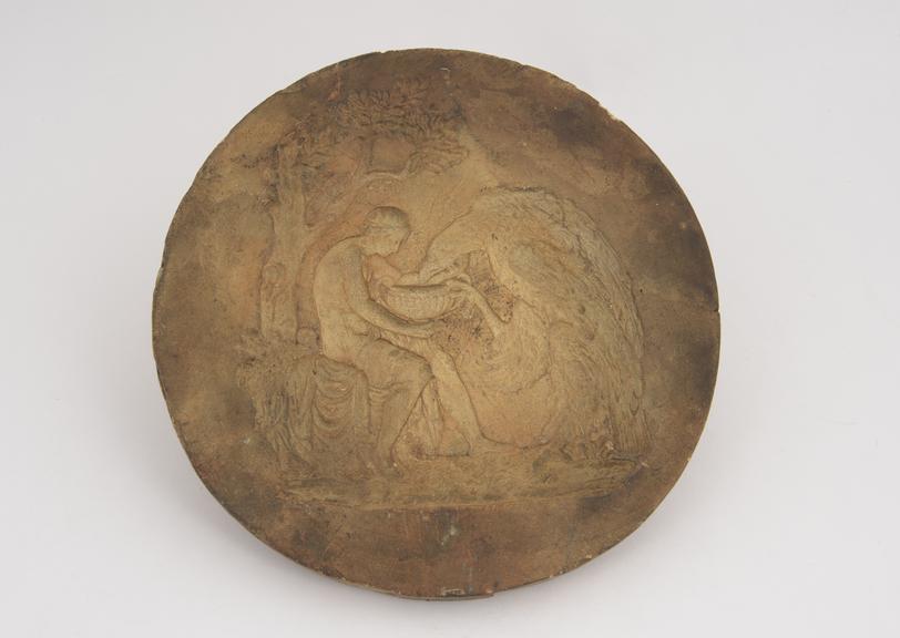 Plaster mould, man seated under tree, feeding eagle out of bowl